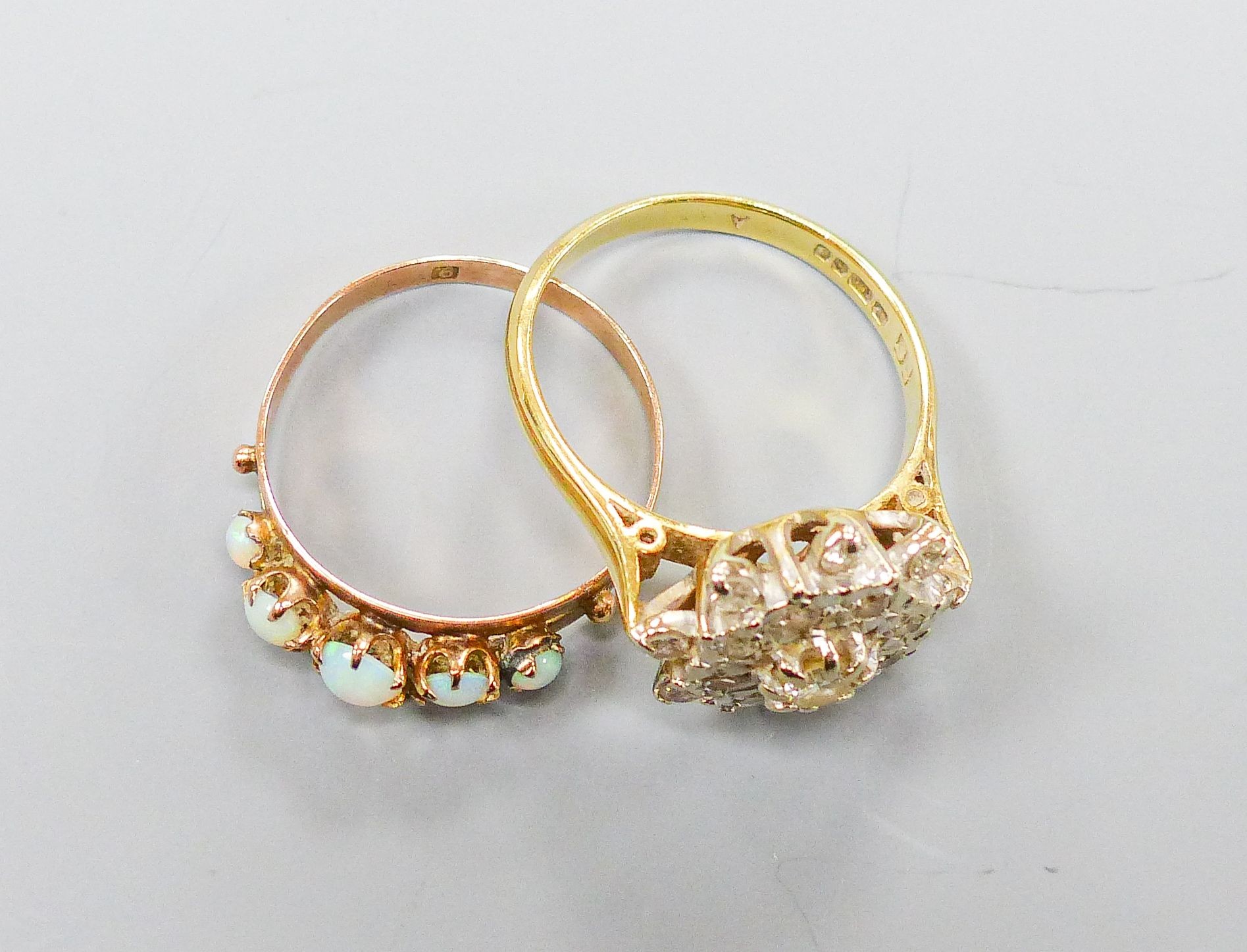 A yellow metal (stamped 9) and graduated five stone white opal set half hoop ring, size M, gross 1.2 grams and and 18ct gold and diamond chip cluster ring, gross 4.6 grams.